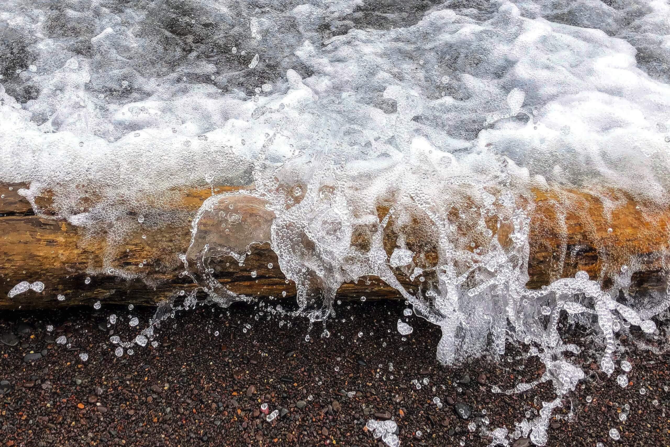 Lake Landscape Fine Art titled Breaching the Wall, capturing a wave over a log near Two Harbors.