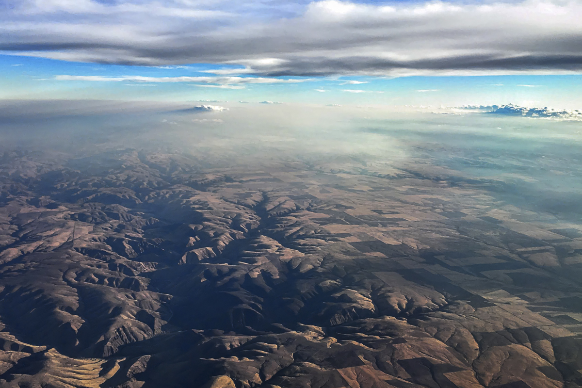 Abstract Landscape Fine Art titled Earth and Sky, aerial view of rugged terrain and blue sky.